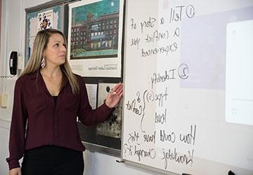 Aimee Marsland Ryan writing on a classroom whiteboard