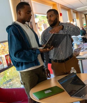 People standing, holding laptop, talking together about what's on the screen