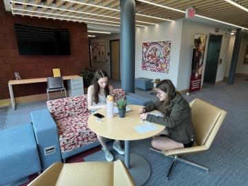 Older children writing at a table in a modern lobby