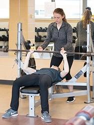 Student assisting another student with bench press