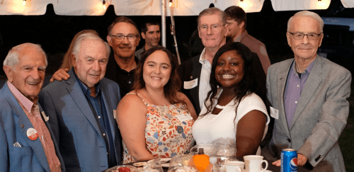 Seven alumni looking at the camera for a picture at an alumni event