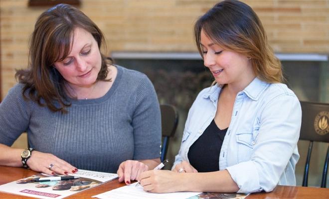 RIC student with staff member completing forms