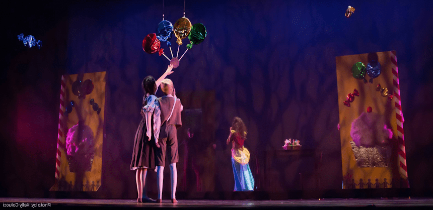 two children reaching for colorful balloons